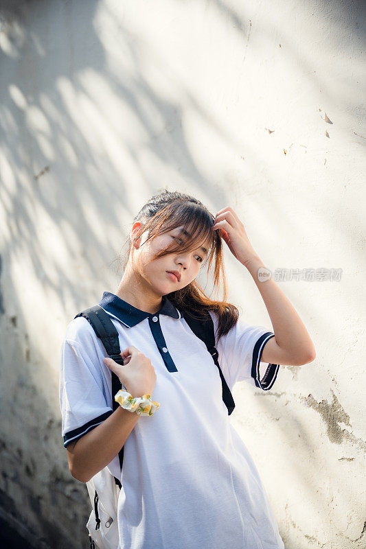 一个美丽的亚洲女孩背着书包在阳光下
