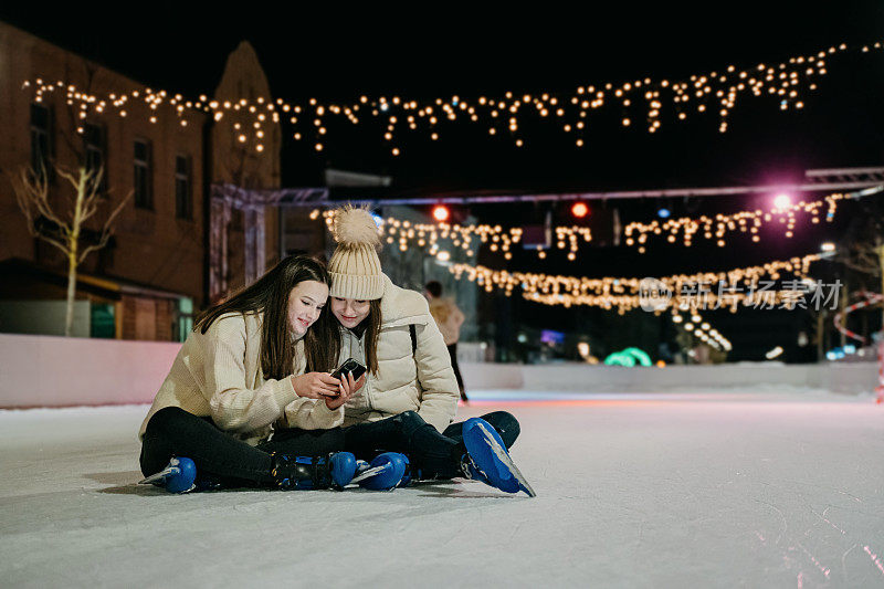 晚上坐在溜冰场上看手机的年轻女性