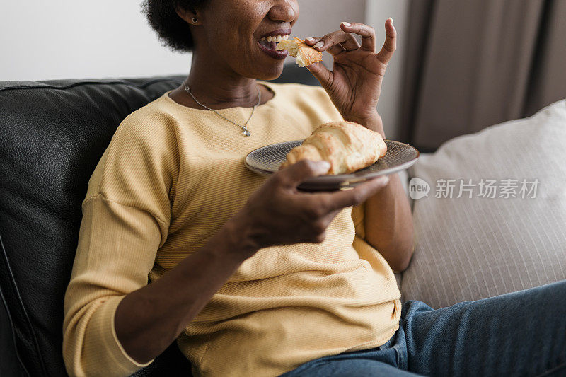 一个年轻女人在家里吃牛角面包的特写