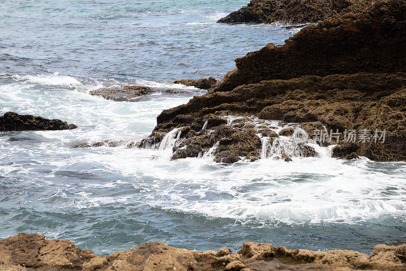 海浪的泡沫拍打着海岸线的岩石