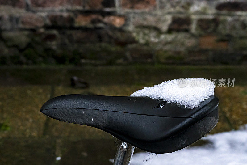 雪中的剑桥公共街道，前景中有一辆自行车靠在栏杆上