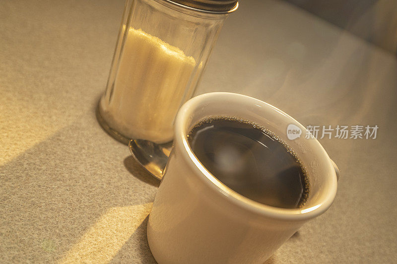 日出时分，餐厅里只有一杯热气腾腾的咖啡和一个糖机