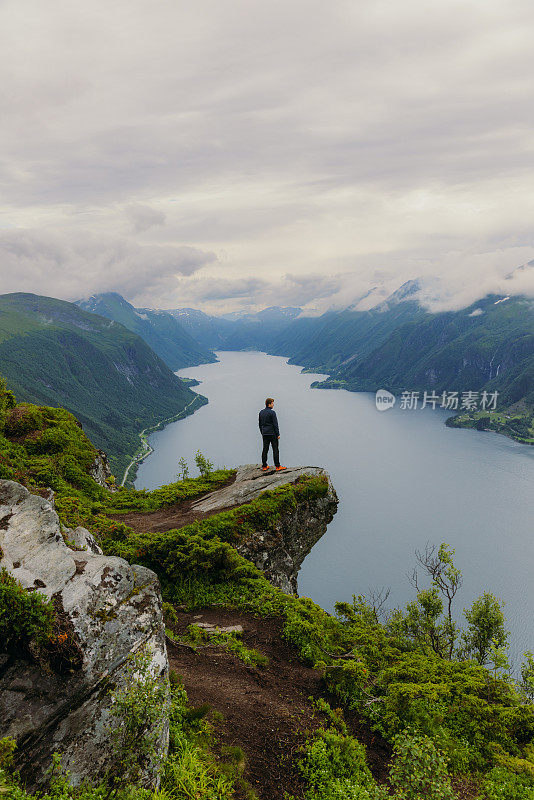 一个人在山顶上俯瞰夏天挪威峡湾的侧视图