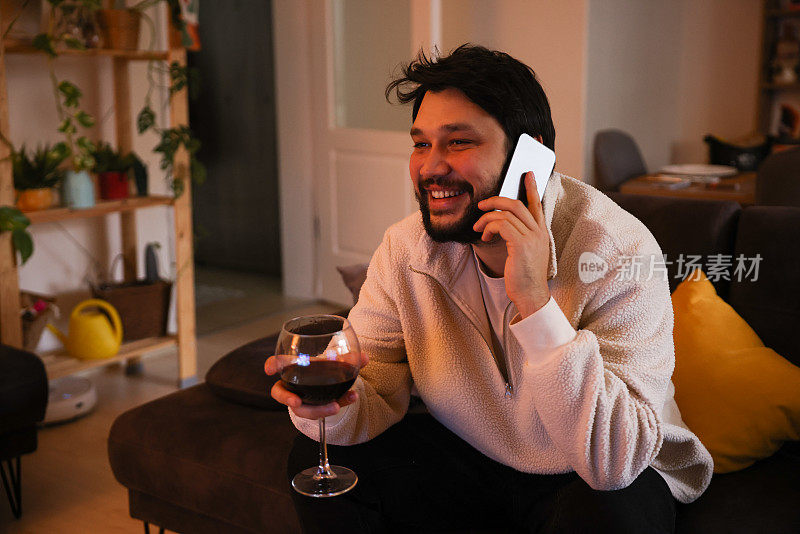 年轻人在家里一边喝红酒一边用智能手机
