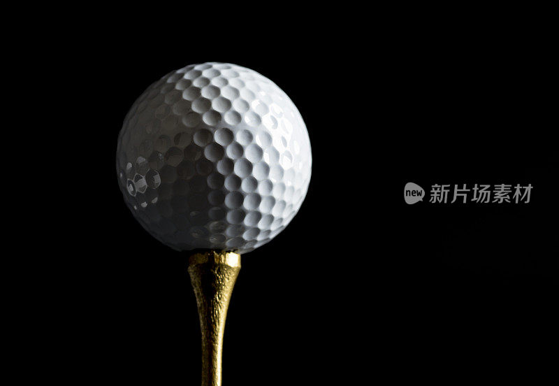 在金色Tee上的高尔夫球与黑色背景