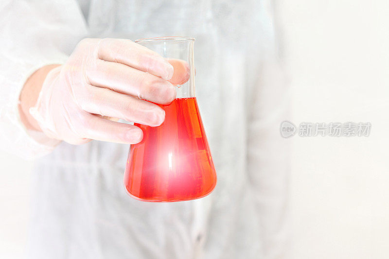 科学发现，科学家拿着装有红色液体的化学玻璃烧瓶