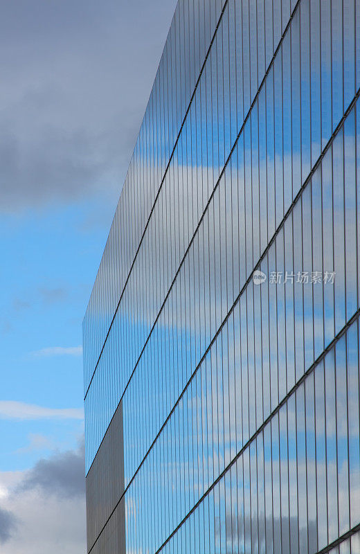 多云的天空反射在现代玻璃建筑。
