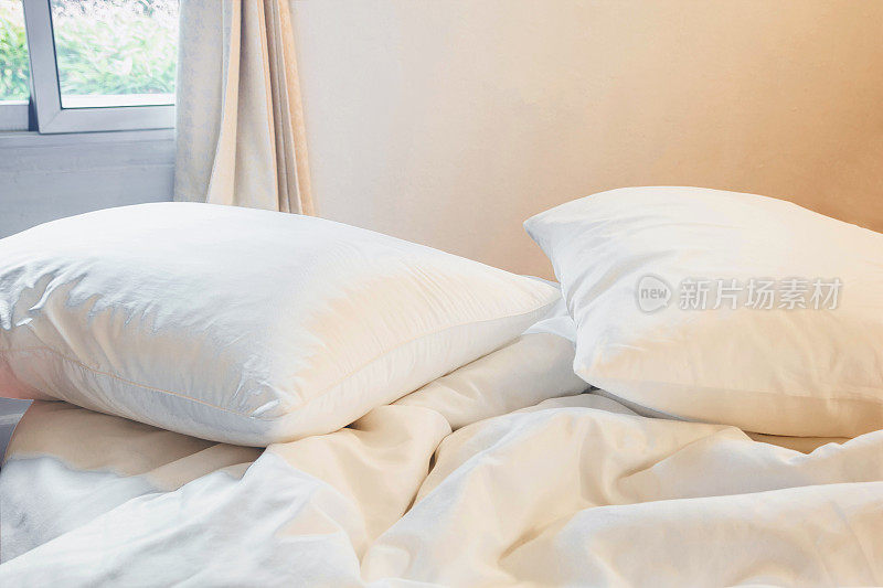 白色的枕头和褶皱的毯子凌乱地放在床上，卧室的左上方有灯光，从漫长的冬夜中入睡。
