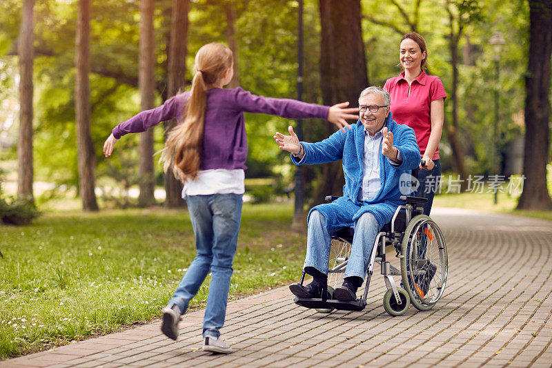 快乐的残疾祖父与他的孙女和女儿在一起