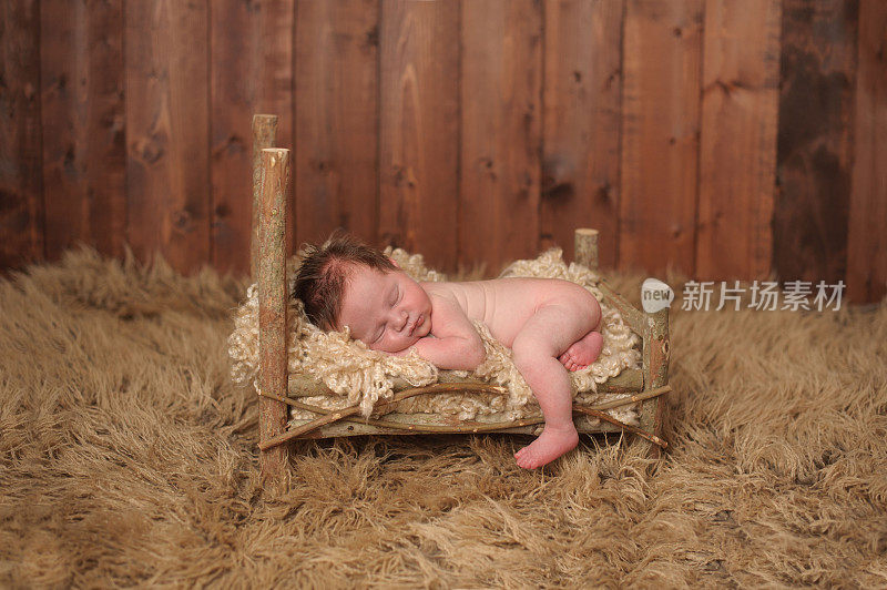 新生婴儿睡在木床上，脚悬空