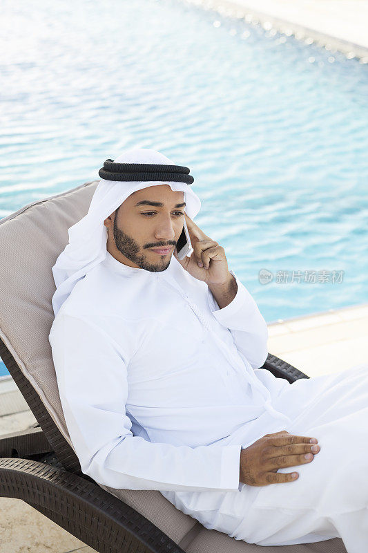 在游泳池边打电话的穆斯林男子