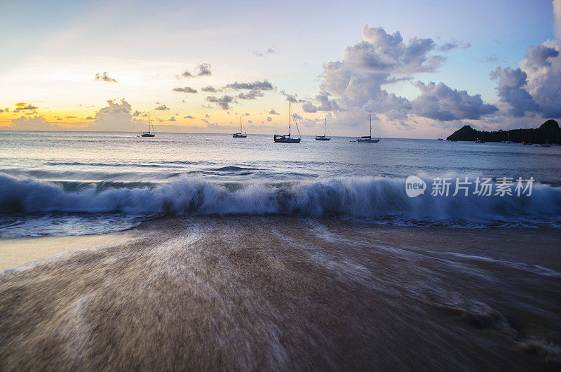 日落时分，海滩上有远处游艇的波浪