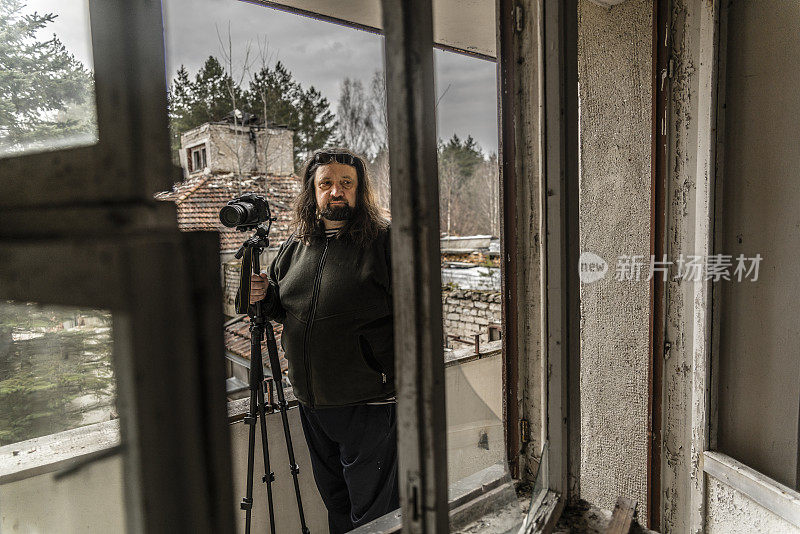 一个成熟的男人，50岁留着胡子和长发的白种人，摄影师，在白俄罗斯拍摄被遗弃的度假胜地