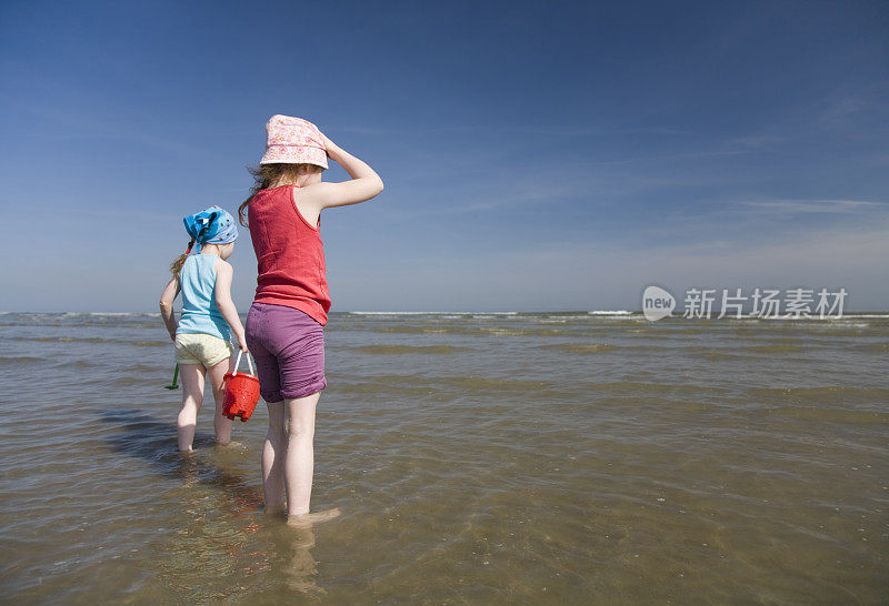 小女孩们赤脚在海边玩耍