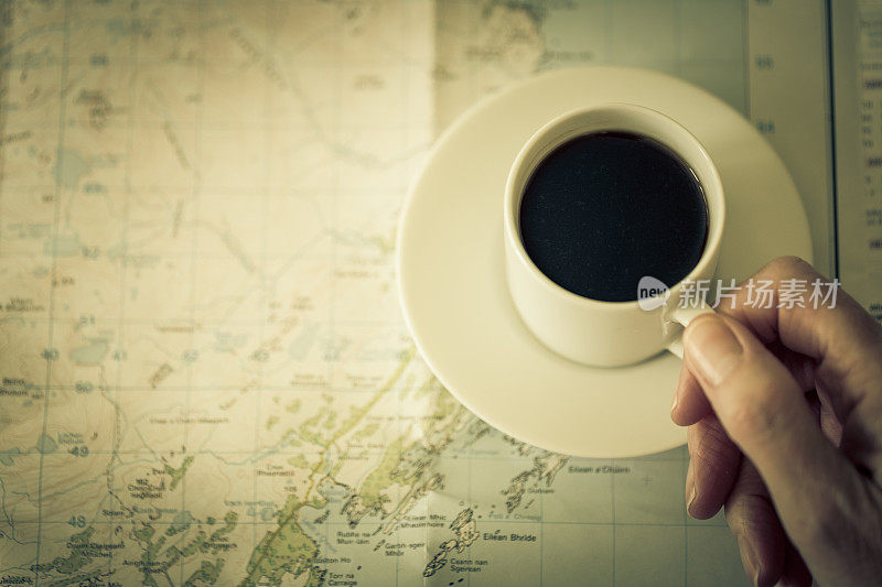手里拿着一杯黑咖啡在地图上