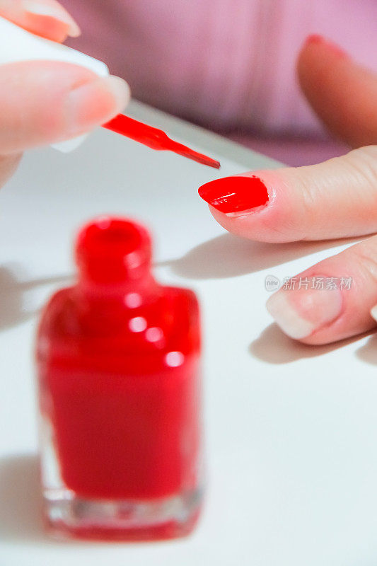 一瓶红色指甲油涂在手上