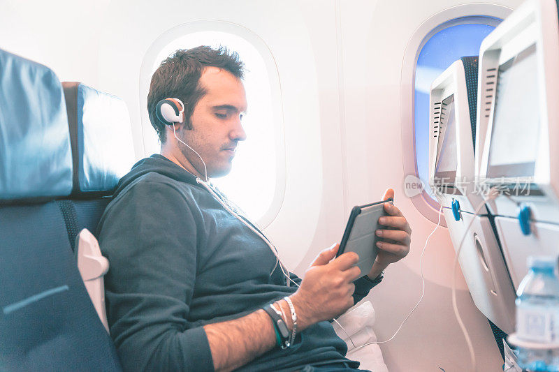 一个坐在飞机上看平板电脑的人