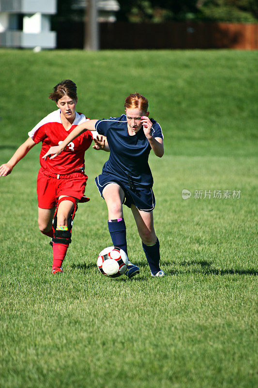 两个年轻的女足球运动员为球与copyspace