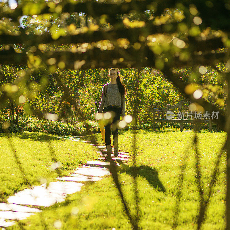 秋天，一个少女在公园的小路上散步
