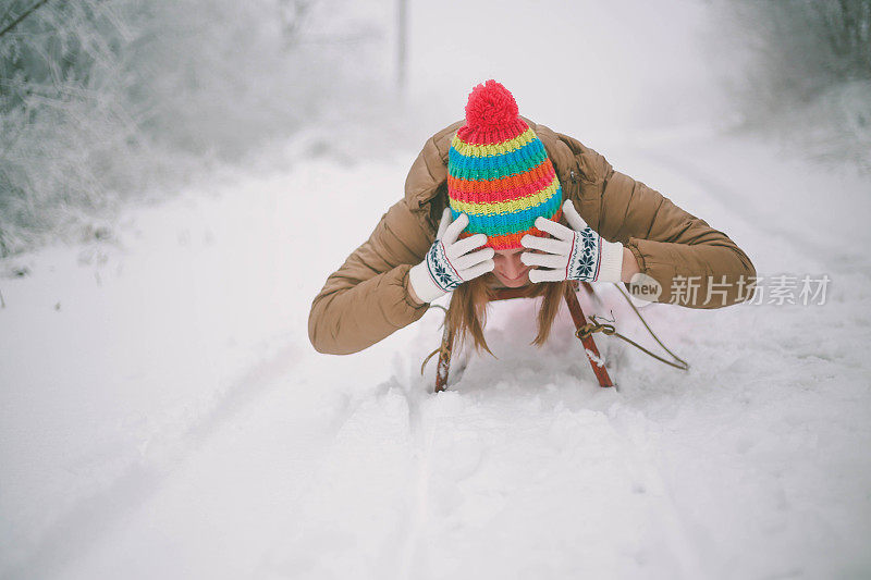 快乐的年轻女子在一个快速的雪橇骑下冰冷的斜坡