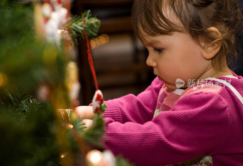 小女孩挂着圣诞树上的装饰品