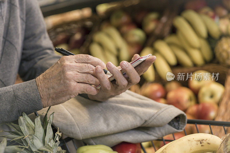 一名男子手拿购物清单在超市里