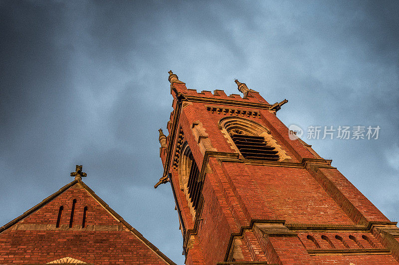 红砖维多利亚时代的教堂塔映衬着暴风雨的天空