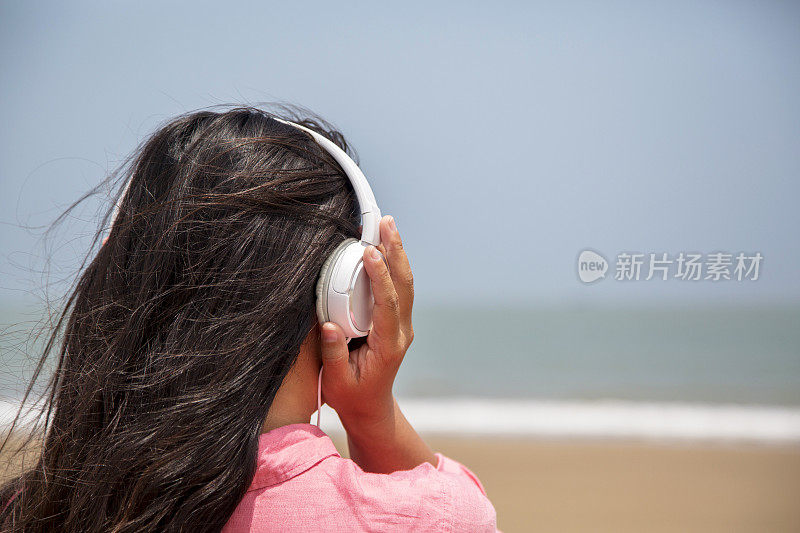 女孩戴着耳机，面朝大海