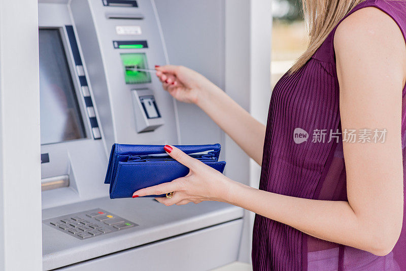 年轻的成年女孩在自动取款机上插入信用卡