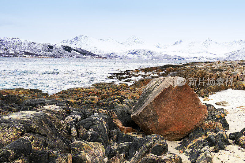挪威特罗姆瑟附近的科瓦洛伊岛有岩石海岸和白雪皑皑的山脉