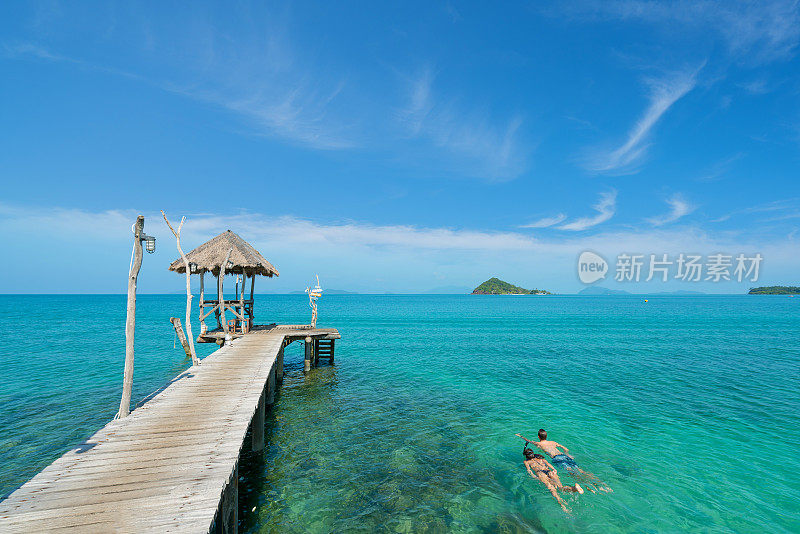 在泰国普吉岛热带度假胜地附近，一对年轻的游客在水晶绿松石般的水中潜水。夏季，假期，旅游和假日概念。
