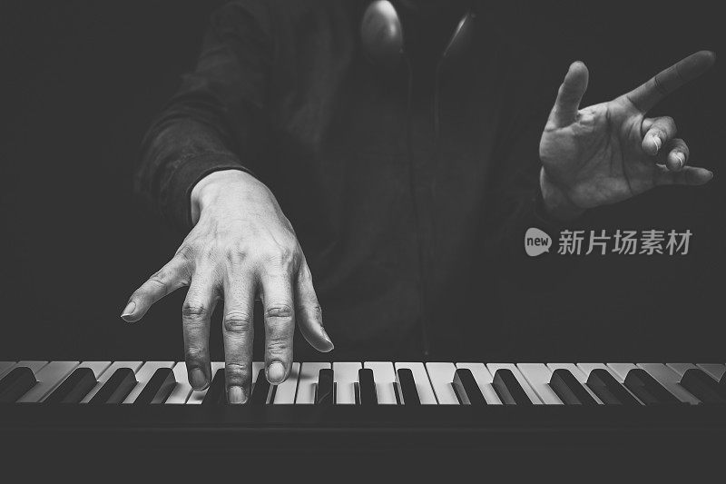 音乐家的手在钢琴键上弹奏，黑白相间