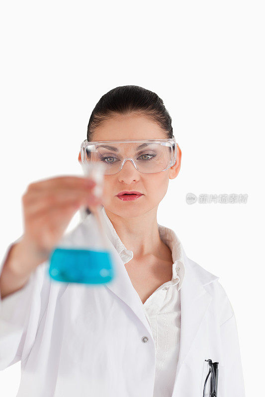 戴着安全眼镜，手持蓝色烧瓶的女科学家