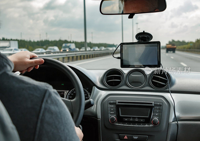 男人开车时双手放在方向盘上，使用GPS导航