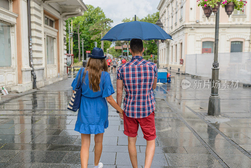 一对年轻夫妇在雨天走在街上