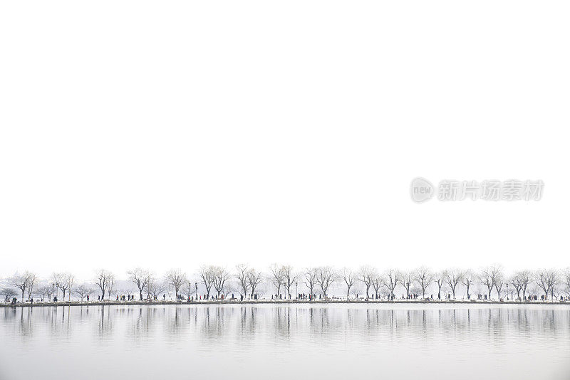 西湖景观，杭州，中国，人们走在湖面上，而在冬天的一天，雪，在湖的倒影
