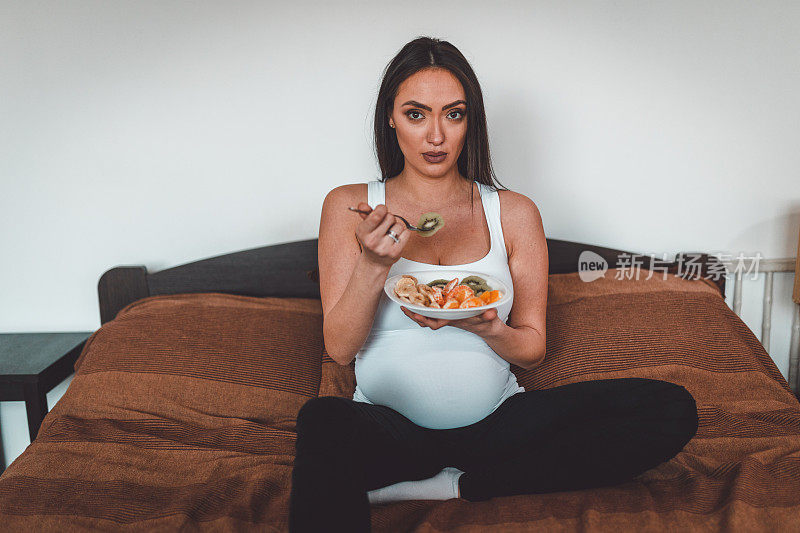 漂亮孕妇坐在床上吃沙拉