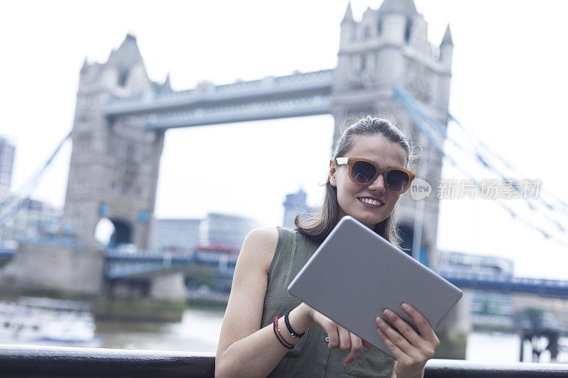 年轻女子在塔桥上用平板电脑