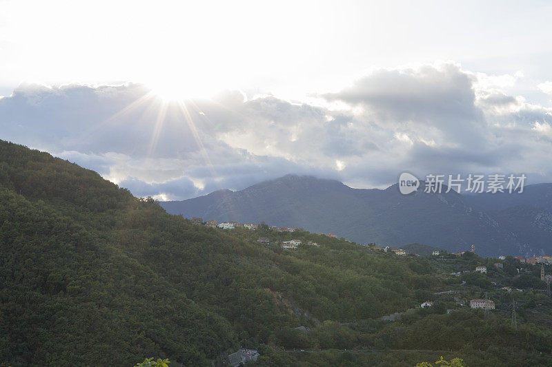 阳光从云层中照射出来，越过山峦和村庄