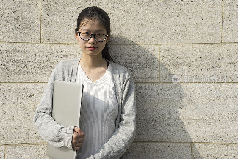 年轻女子拿着笔记本电脑看着摄像头