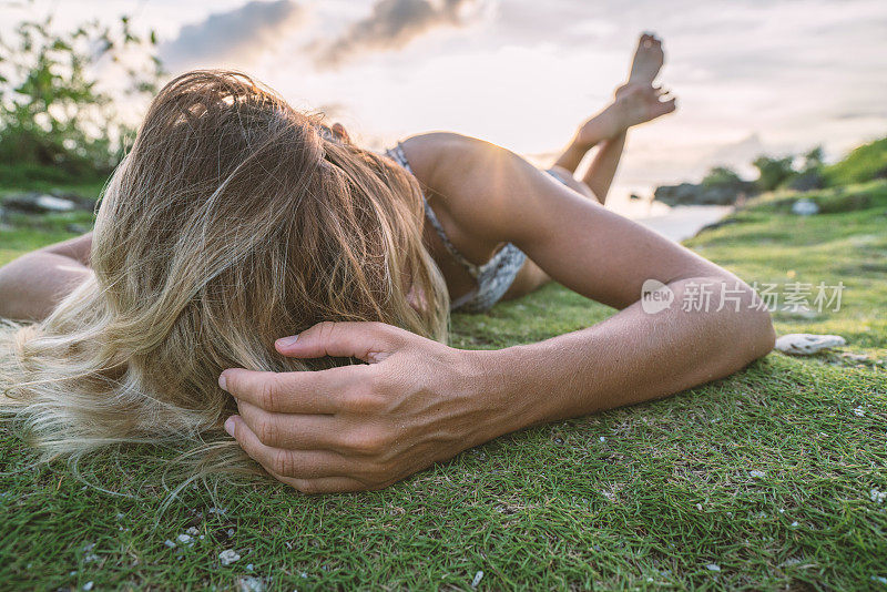 年轻女子在热带岛屿放松日落，性感