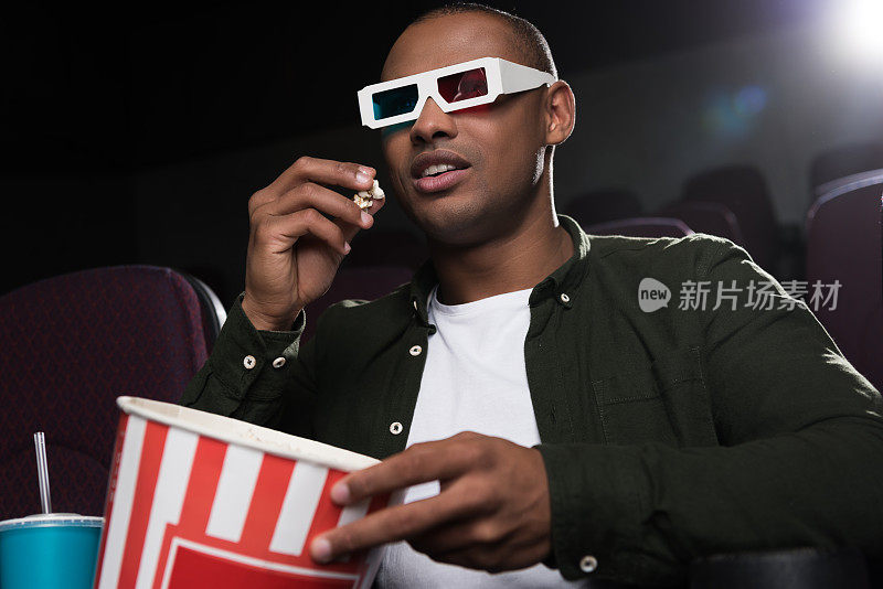 戴着3d眼镜的非裔美国人在电影院吃爆米花看电影