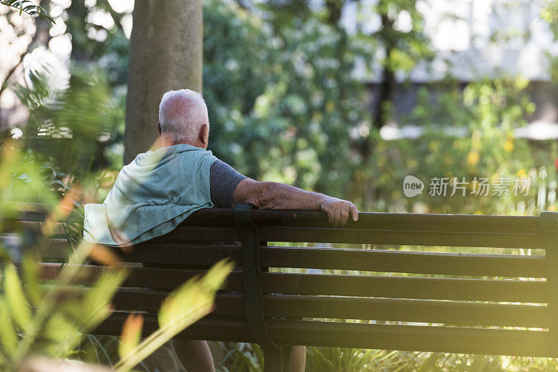 一位老人坐在户外的长椅上