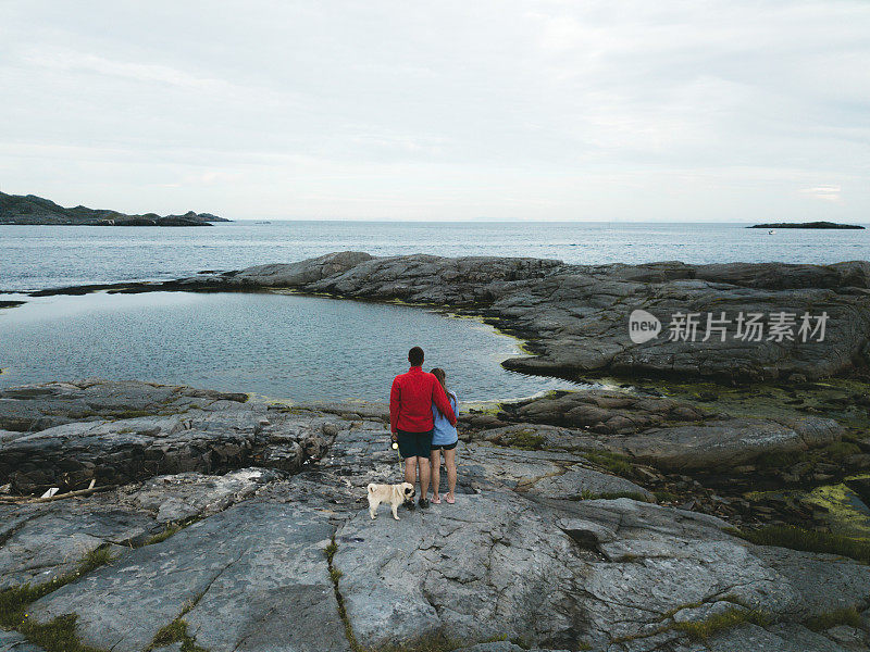 在罗浮敦群岛上，一对夫妇抱着狗看海