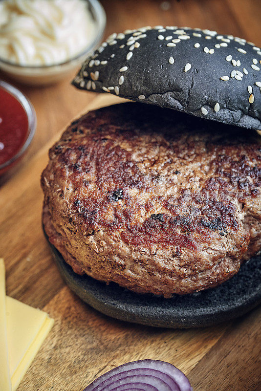 黑汉堡面包配牛肉饼，芝士，番茄和生菜