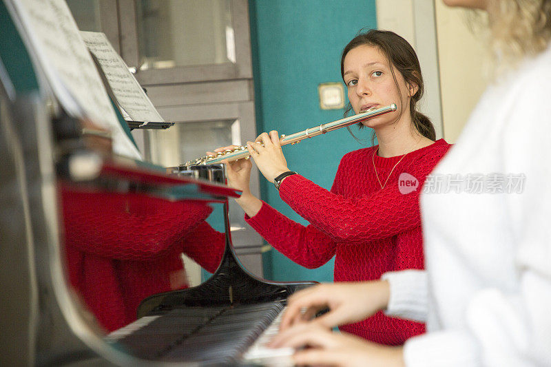 年轻女子在弹钢琴和吹长笛
