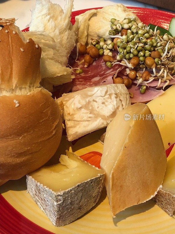 在印度德里的酒店餐厅的自助早餐中，奶酪拼盘上有精选的法国奶酪、切达干酪、豪达干酪、帕尔马干酪、卡门贝尔奶酪、瑞士奶酪、绿豆、蔬菜沙拉、鹰嘴豆泥、黑豆芽和法式面包