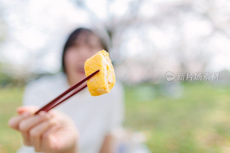 一个无法辨认的人用筷子夹着日式烤鱼烧