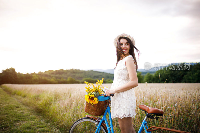 骑着自行车的女人在麦田里。