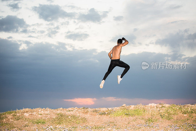 年轻的运动员在空中跳得很高，田园风光。